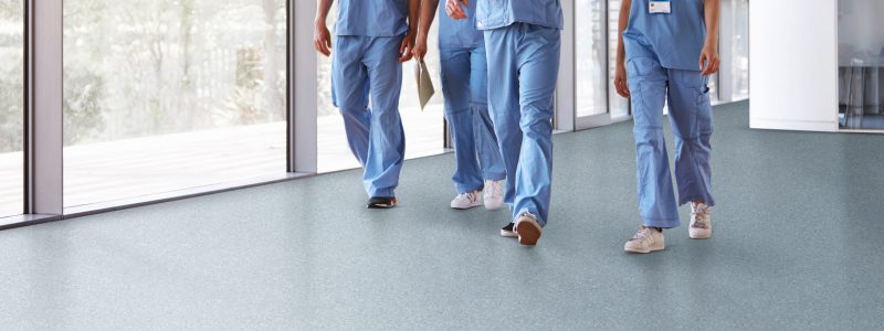 Four healthcare workers in scrubs walking in corridor